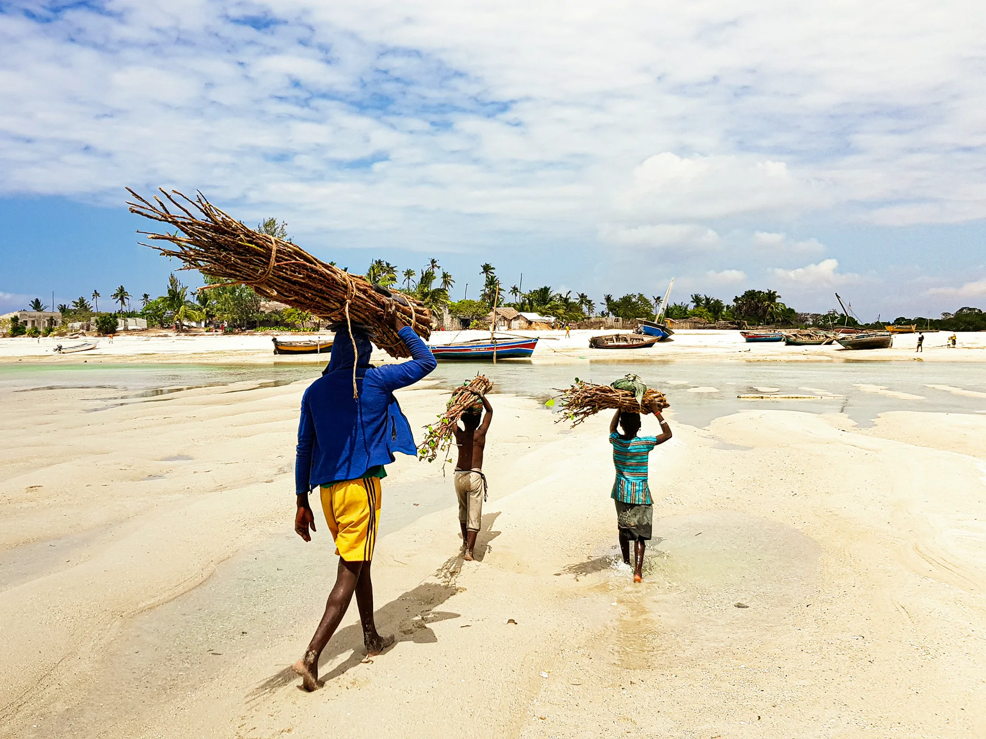 Pêcheurs mozambicains portant leur récolte sur la plage au lever du soleil